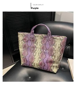 Detail view of large tote bag featuring purple snakeskin print on a black leather chair