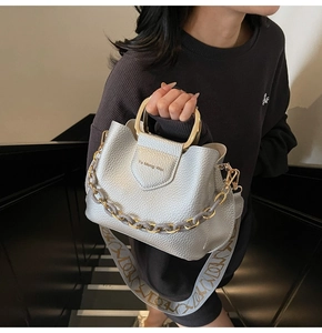 Detail of silver pebble leather bucket bag with gold U-shaped handle and chain strap