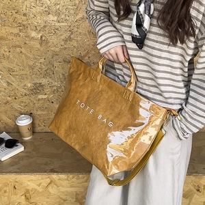 Close-up of brown crinkle texture tote bag with white TOTE BAG text and yellow strap