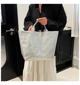 Chic silver metallic DuPont paper tote bag worn by a model in a minimalist home setting