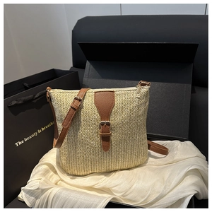 Detail of beige straw woven crossbody bag with brown lychee leather strap and silver metal buckle