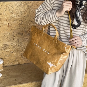 Brown tote bag with crinkled texture and white TOTE BAG text shown with shoulder strap
