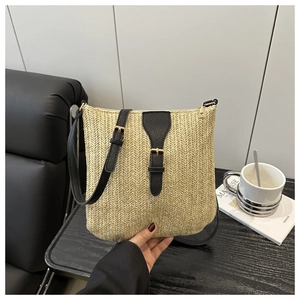 Detail of herringbone straw weave texture with black leather trim and gold metal hardware