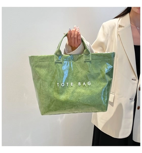 Detail of green waterproof tote bag featuring a transparent PVC layer and inner paper texture