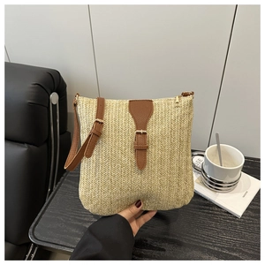 Detail of woven straw crossbody bag with brown leather strap and metal zipper closure