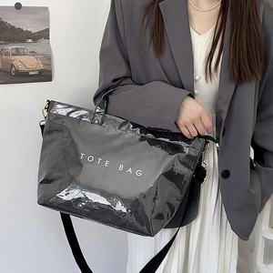 Chic black patent leather tote bag styled with a gray blazer and a long white skirt