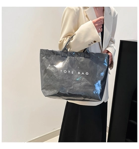 Detail of black dual-layer tote bag with glossy finish and bold TOTE BAG typography