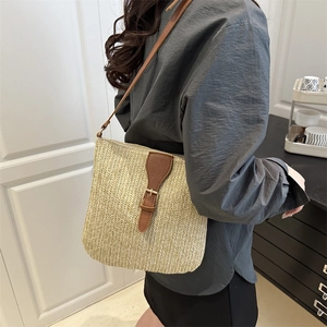 Minimalist straw crossbody bag with brown leather strap shown on a model from the side