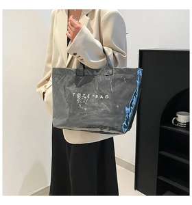 Close-up of a glossy gray Tyvek tote bag with white TOTE BAG print worn by a model