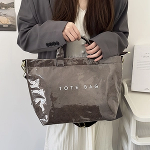 Close-up of a large glossy grey tote bag featuring white lettering and adjustable straps