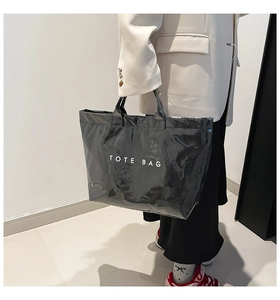 Glossy black Tyvek tote bag featuring bold white TOTE BAG lettering and polished handles