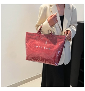 Detail of burgundy waterproof tote bag with shiny crinkled texture and white logo