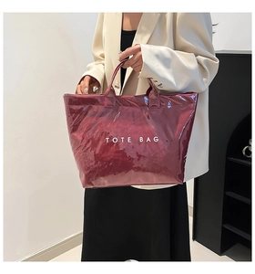 Detail view of dark red glossy patent leather tote bag with white TOTE BAG typography