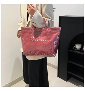 Detailed view of glossy dark red tote bag with printed text on polished surface