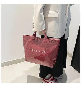 Detail of burgundy waterproof tote bag with white TOTE BAG lettering and glossy finish