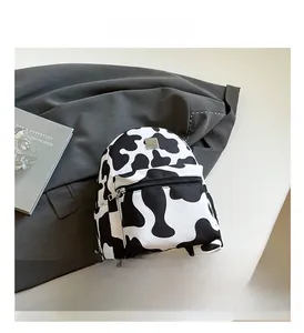 Detailed close-up of cow print fashion backpack with silver logo and front zipper pocket
