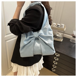 Vue détaillée du sac à bandoulière en denim avec grand nœud porté sur un blazer