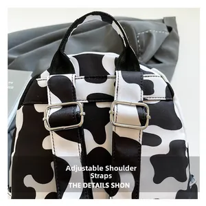 Detail view of adjustable black straps with silver buckles on cow print backpack