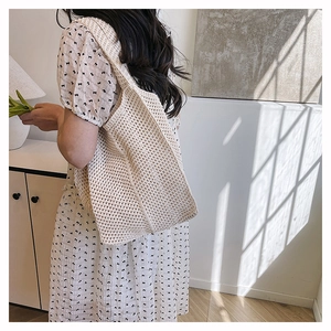 Détail d'un sac cabas en crochet beige montrant la texture en maille ajourée au soleil