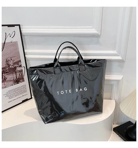 Close-up of shiny black waterproof tote bag with white text on a wavy display stand