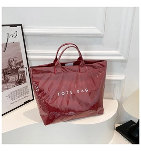 Glossy dark red waterproof tote bag with white text displayed on a modern white stand