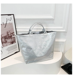 Close-up of metallic silver DuPont paper tote bag with TOTE BAG print on white display stand