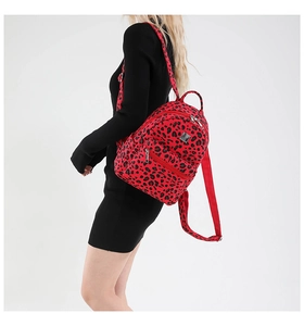 Red canvas backpack with black leopard print pattern worn by model on black dress
