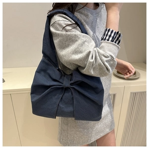 Detail of deep blue denim tote bag featuring a large decorative bow and washed texture