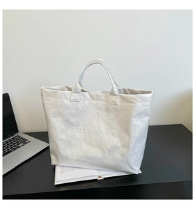 Detail showing the embossed TOTE BAG text on white wrinkled waterproof DuPont paper bag