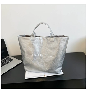 Detail of silver metallic tote bag with wrinkled texture and Tote Bag lettering print