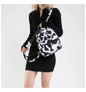 Close-up of mini cow print backpack with adjustable straps and silver metal zippers
