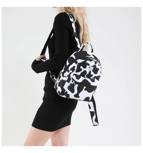 Mini backpack with black and white cow print, zipper pockets and metal plate detail