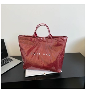 Close-up of wine red waterproof DuPont paper tote bag with white text on a desk