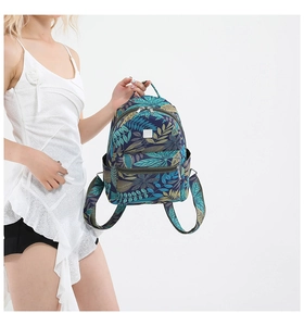 Tropical leaf print backpack in navy blue with adjustable straps shown by a model
