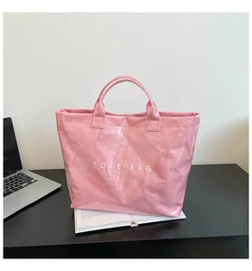 Detailed view of a pink DuPont paper tote bag with glossy texture and text on a desk