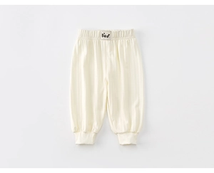 Detailed macro view of cream-colored knit joggers with elastic waist and bear patch