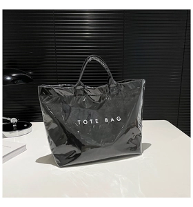 Detailed view of shiny black waterproof tote bag featuring bold white TOTE BAG lettering