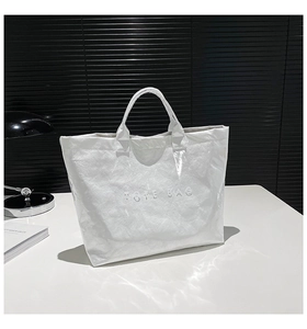 Close-up of a white textured tote bag with embossed letters on a minimalist desk