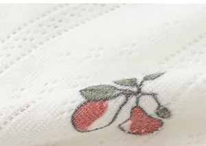 Macro detail of breathable white cotton hollow knit fabric with red berry and green leaf print