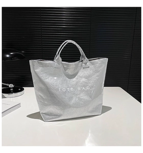 Close-up of metallic silver tote bag with unique crinkled texture and TOTE BAG text