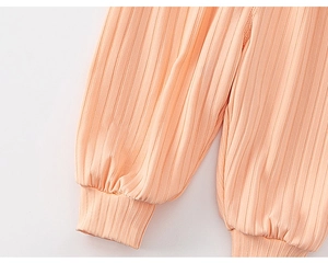 Close-up of ribbed knit texture and elastic cuff on light orange toddler trousers