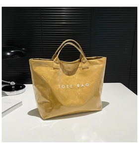Detail view of yellow tote bag with unique crinkle texture and white printed lettering