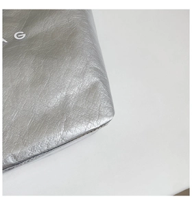 Detailed macro view of silver crinkled texture bag featuring a white letter G logo