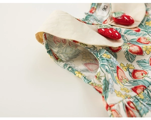 Dettaglio vestito da neonata con grande colletto beige e applicazioni 3D a fragola