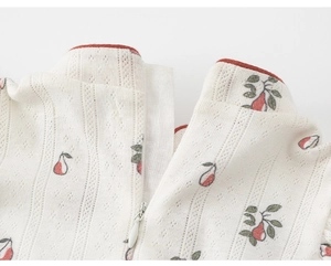Close-up of white knitted fabric with red pear print and contrast red neck piping detail