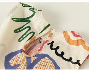 Dettaglio dello scollo dell'abito da bambina con stampa graffiti e bottone sul retro