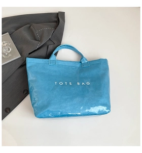 Top view of bright blue waterproof tote bag with white text on white minimalist background