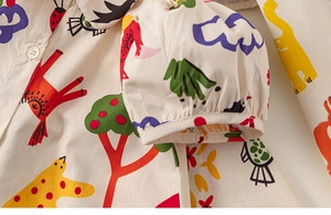 Détail des motifs d'animaux imprimés sur robe en coton beige avec bouton en résine blanc