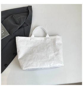 Flat lay of white waterproof Tyvek tote bag with wrinkled texture and embossed letters