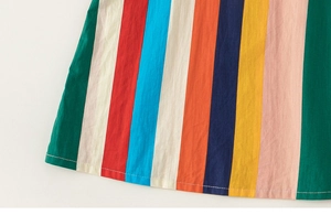 Close-up of the hem stitching on a multi-colored vertical striped cotton girls dress
